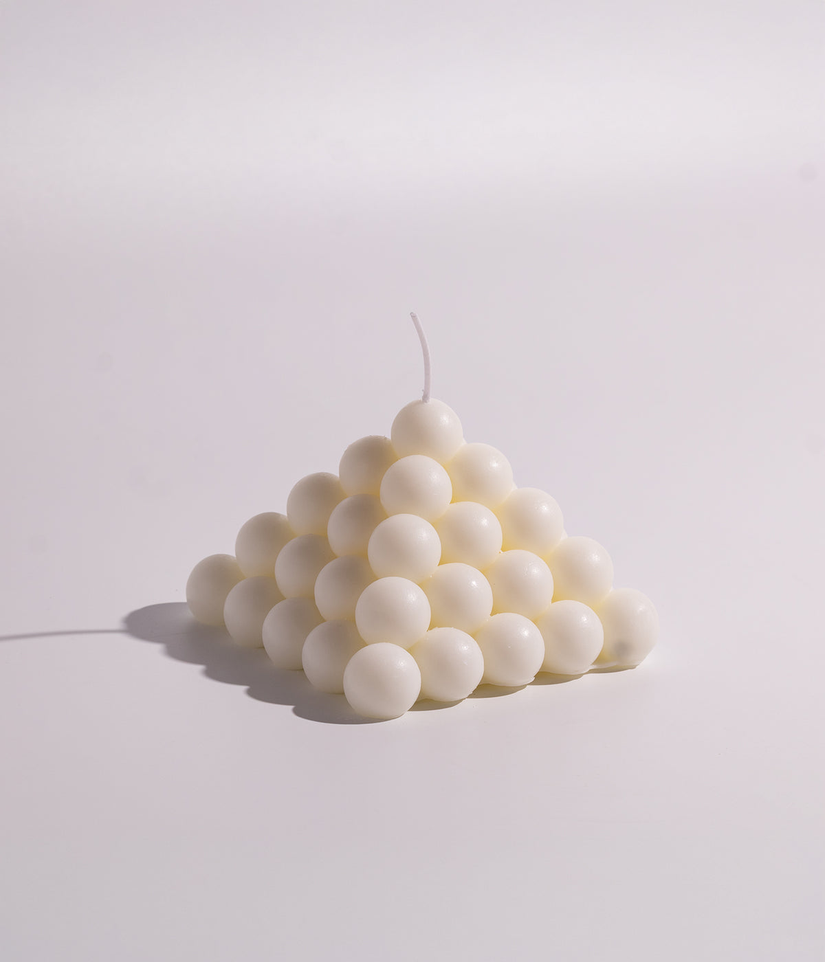 شمعة ديكورية بيضاء بتصميم هرمي على شكل كرات