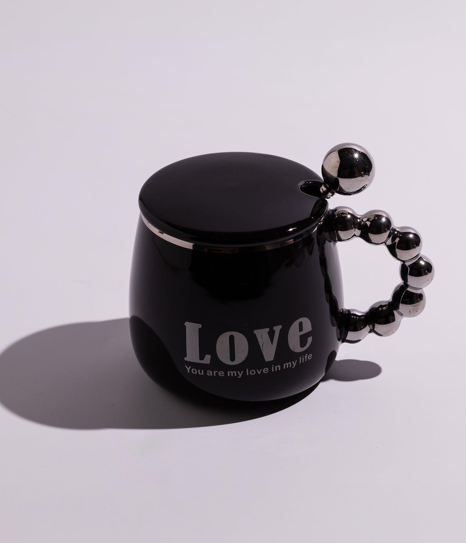 كوب سيراميكي أسود مزين بعبارة LOVE، يأتي مع غطاء وملعقة ومقبض ميتاليك أنيق، مثالي لمحبي التصميم العصري والفخم