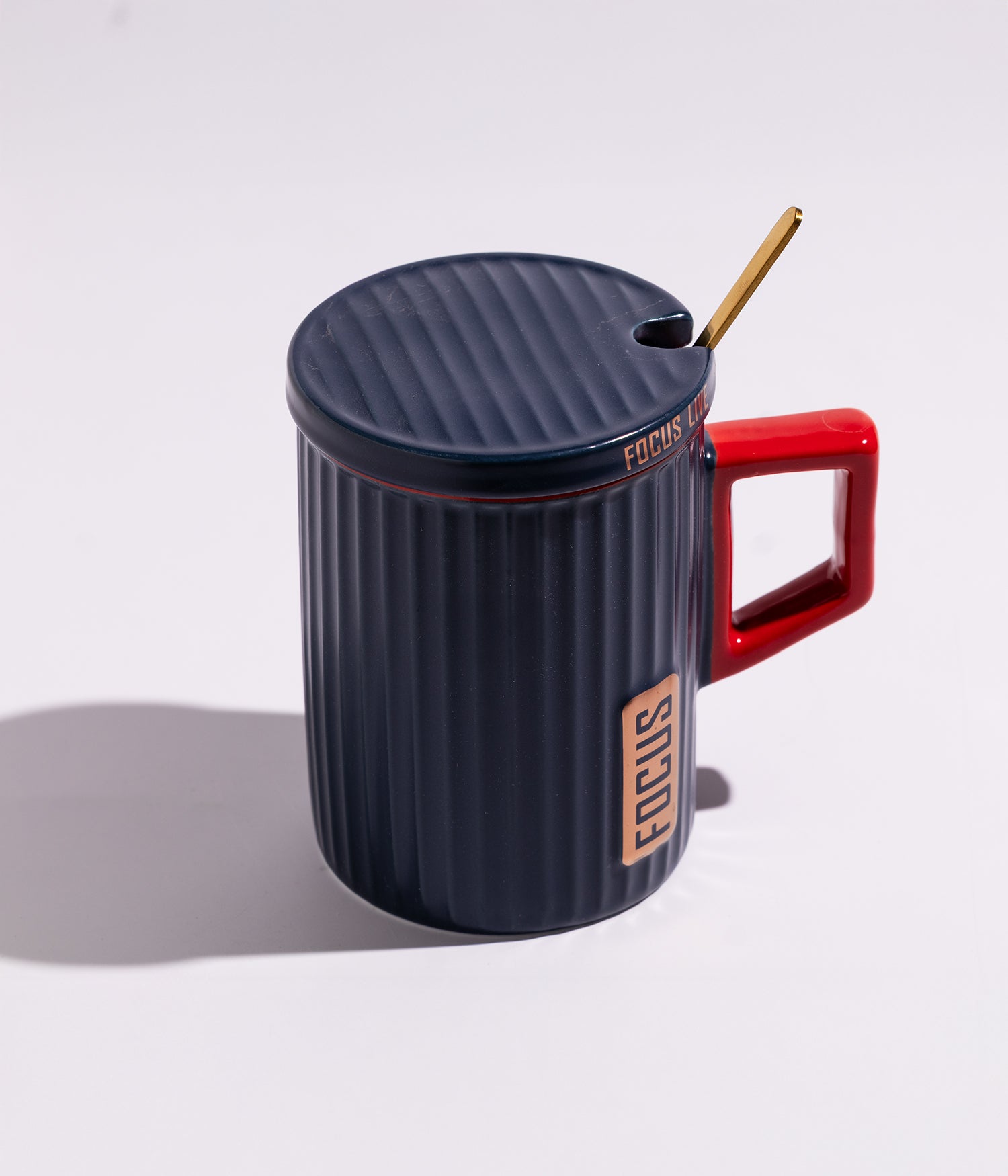كوب قهوة سيراميك بتصميم هندسي مع مقبض ملون وغطاء وملعقة بعبارة «FOCUS» باللون الأزرق