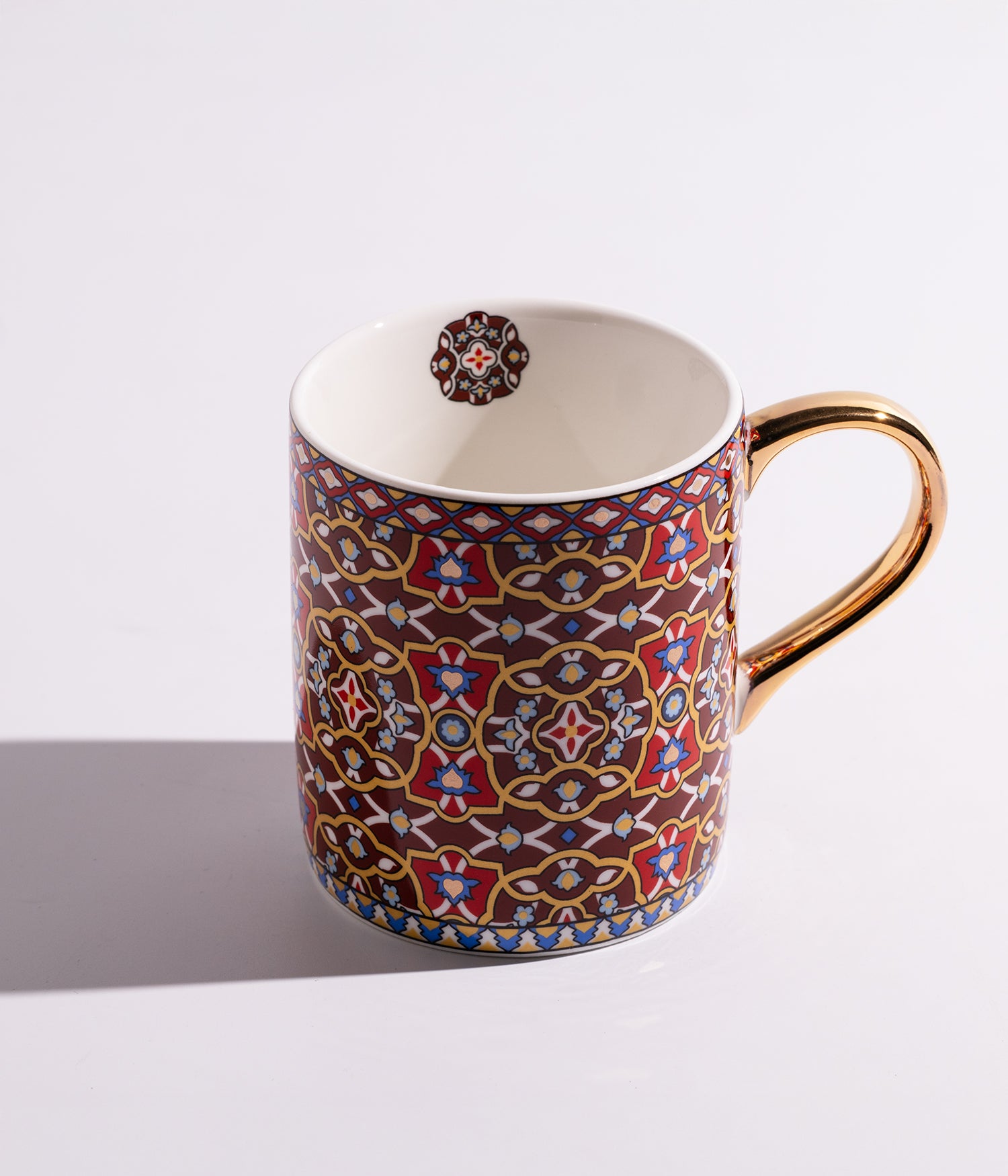 كوب مصنوع من السيراميك مزين بنقوش هندسية شرقية ويتميز بمقبض ذهبي أنيق، مناسب للاستخدام اليومي مع القهوة أو الشاي