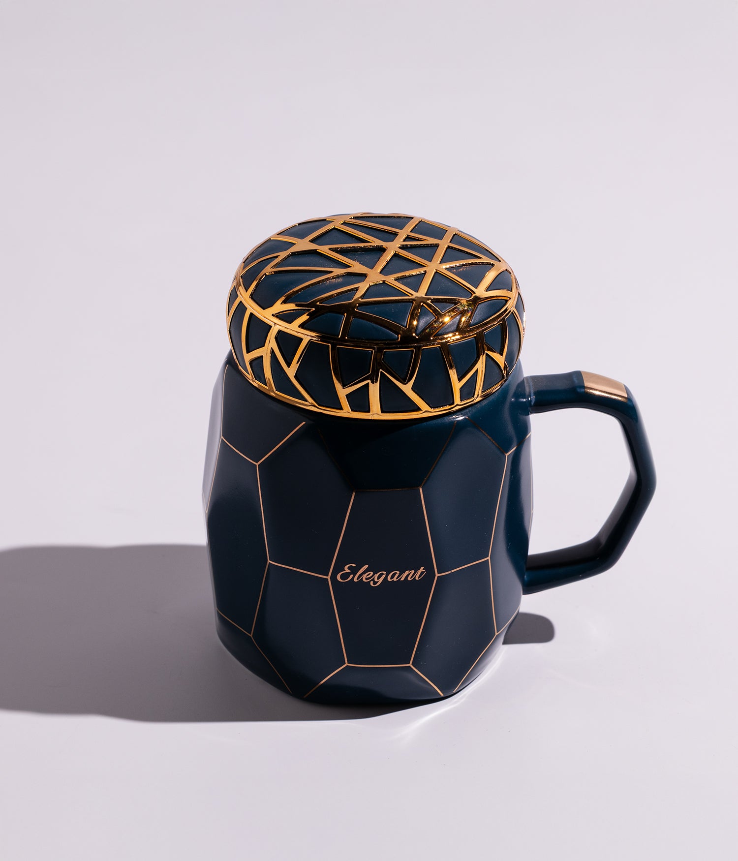 كوب سيراميكي باللون الأزرق الداكن مزين بخطوط ذهبية أنيقة على الغطاء، مناسب للاستخدام اليومي في المنزل أو المكتب