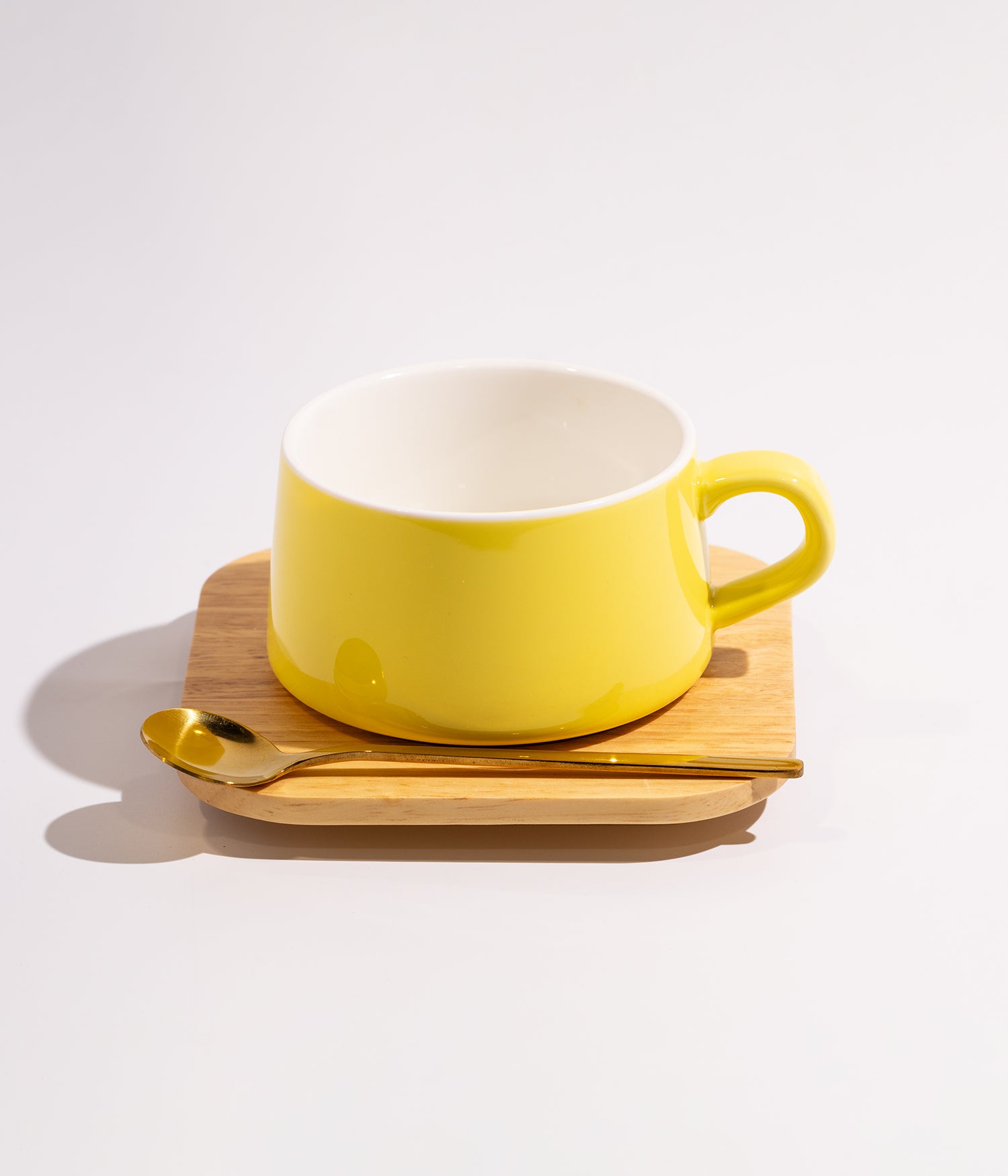 فنجان سيراميك سادة اصفر مع قاعدة خشبية وملعقة