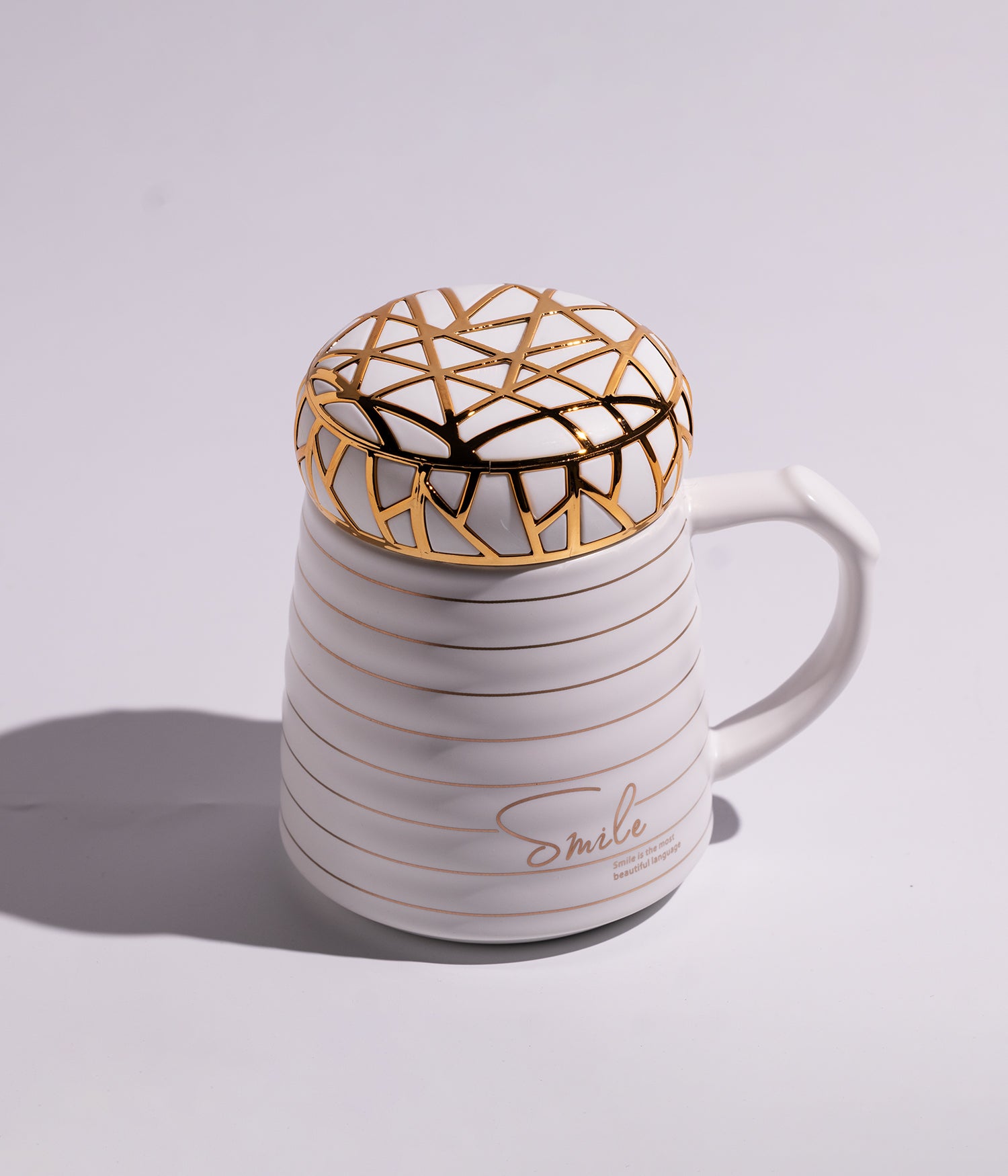 كوب سيراميكي باللون الأبيض مزين بتصميم سمايل، يأتي مع غطاء محكم الإغلاق بتفاصيل مذهب، ملائم للاستخدام اليومي في المنزل أو المكتب