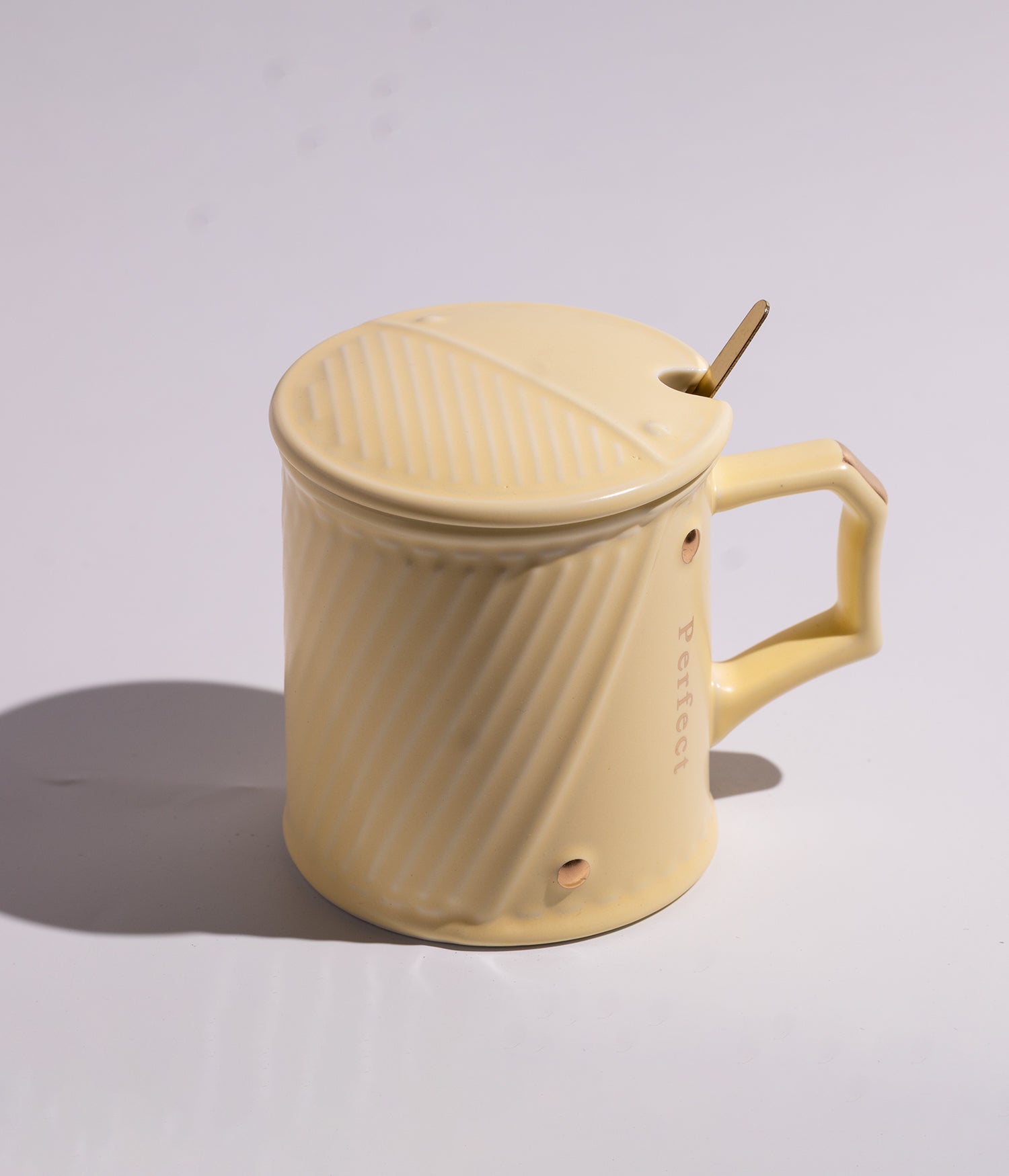 كوب سيراميكي بتصميم خطوط مائلة أنيقة باللون الأصفر، يأتي مع غطاء وملعقة مرفقة، ملائم للاستخدام اليومي في المنزل أو المكتب