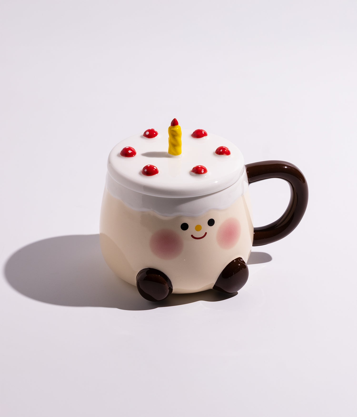 كوب سيراميك بتصميم قالب كيك على الغطاء وشمعة في الوسط