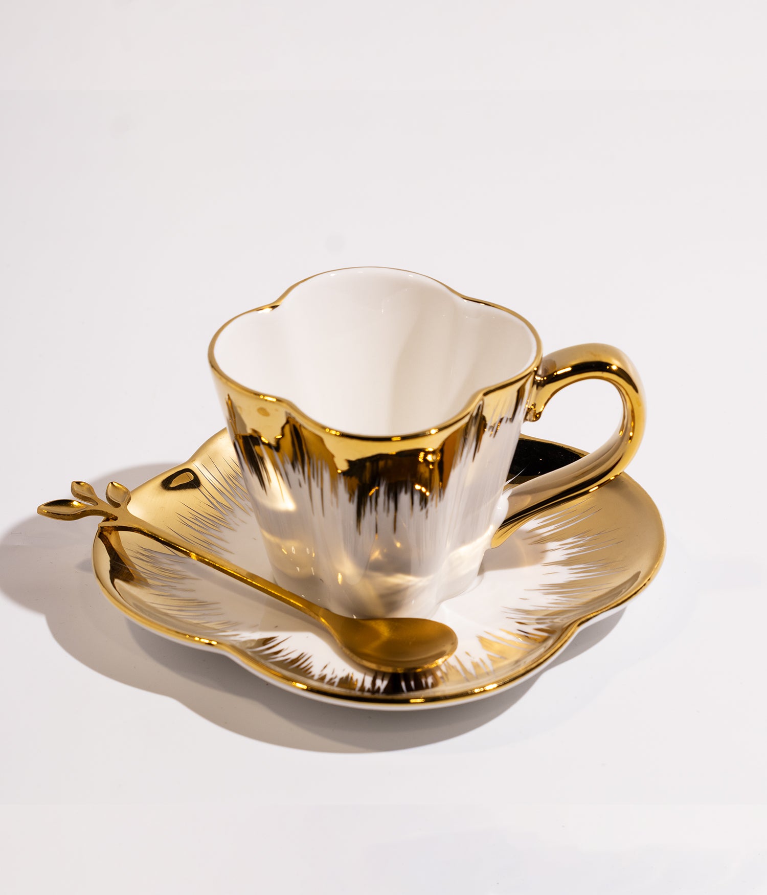 فنجان قهوة بتصميم ذهبي أنيق مع قاعدة وملعقة