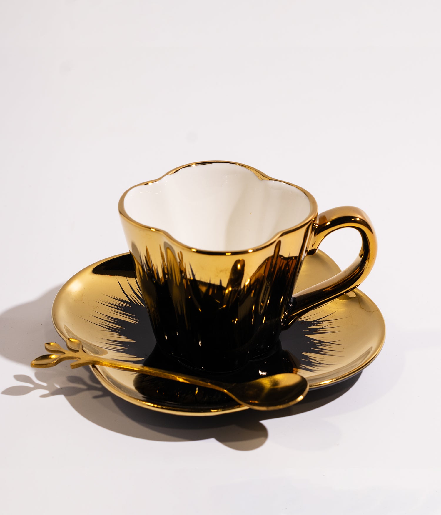 فنجان قهوة بتصميم ذهبي أنيق مع قاعدة وملعقة