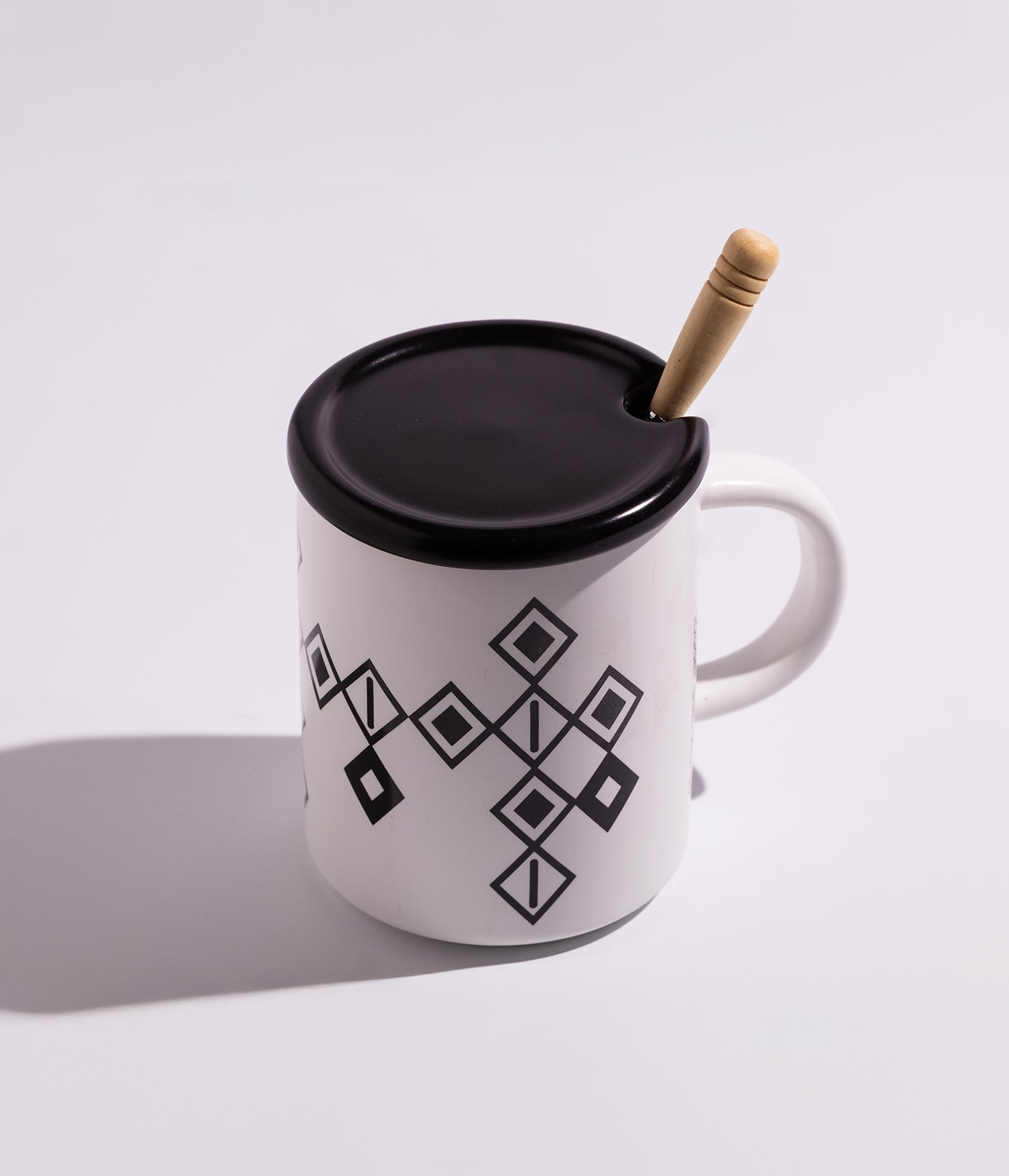 كوب سيراميك بخطوط سوداء مع غطاء وملعقة خشبية