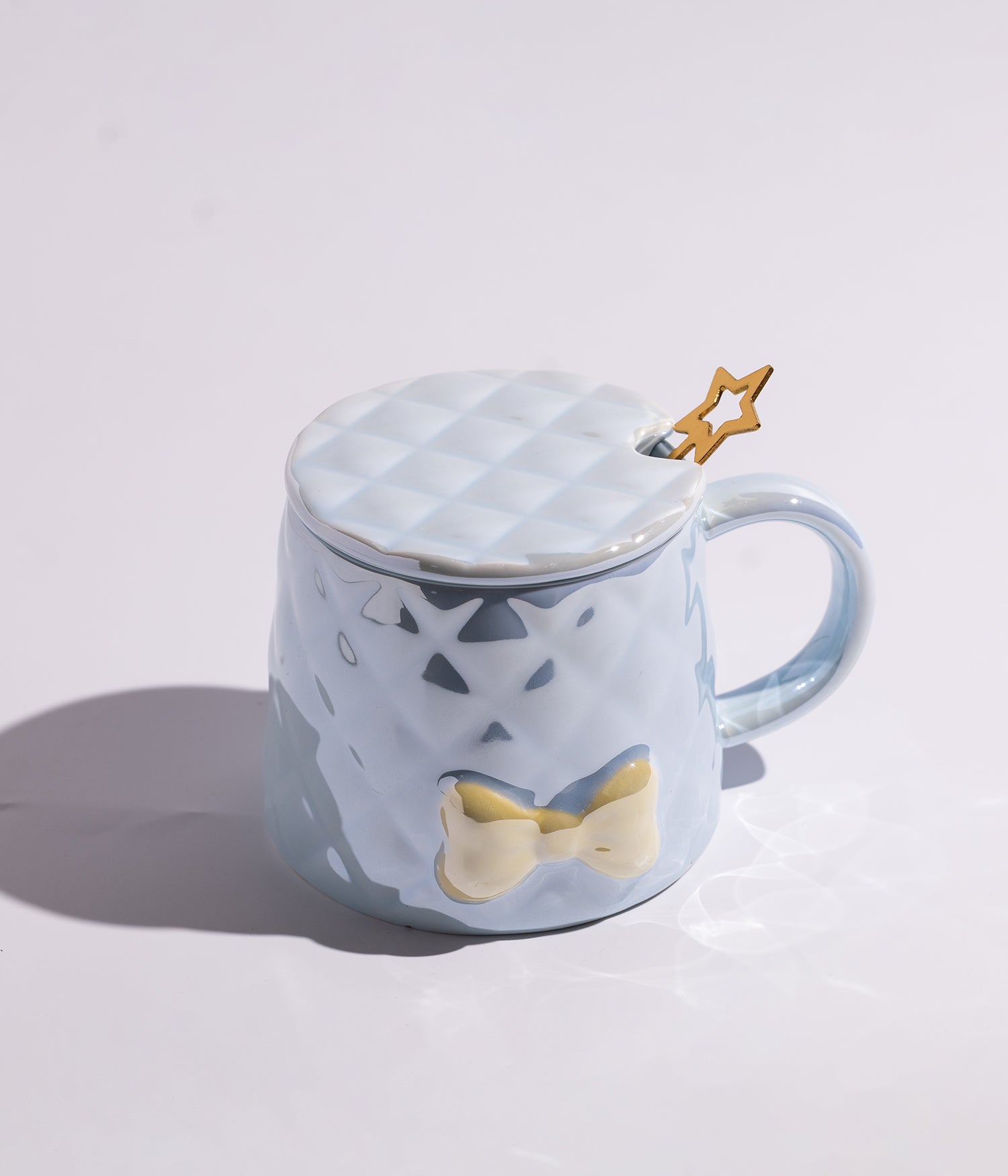 كوب مصنوع من السيراميك باللون الأزرق مزين بتصميم كاروهات وبابيون، مزود بغطاء وملعقة على شكل نجمة، مناسب للاستخدام اليومي مع القهوة أو الشاي
