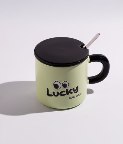 كوب قهوة سيراميك مزين بعبارات ورسوم لطيفة مع غطاء وملعقة بعبارة «LUSKY» باللون الأخضر