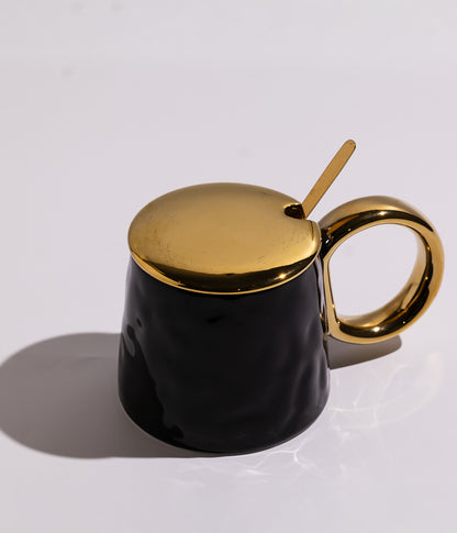 كوب سيراميك بتصميم أنيق مع غطاء ومقبض ميتاليك، مرفق بملعقة معدنية ملونة، باللون الأسود مع غطاء ذهبي