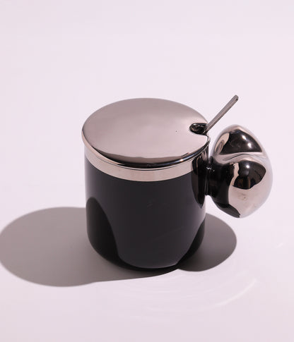 كوب سيراميك بتصميم أنيق مع مقبض فريد، مزود بغطاء فضي وملعقة، باللون الأسود