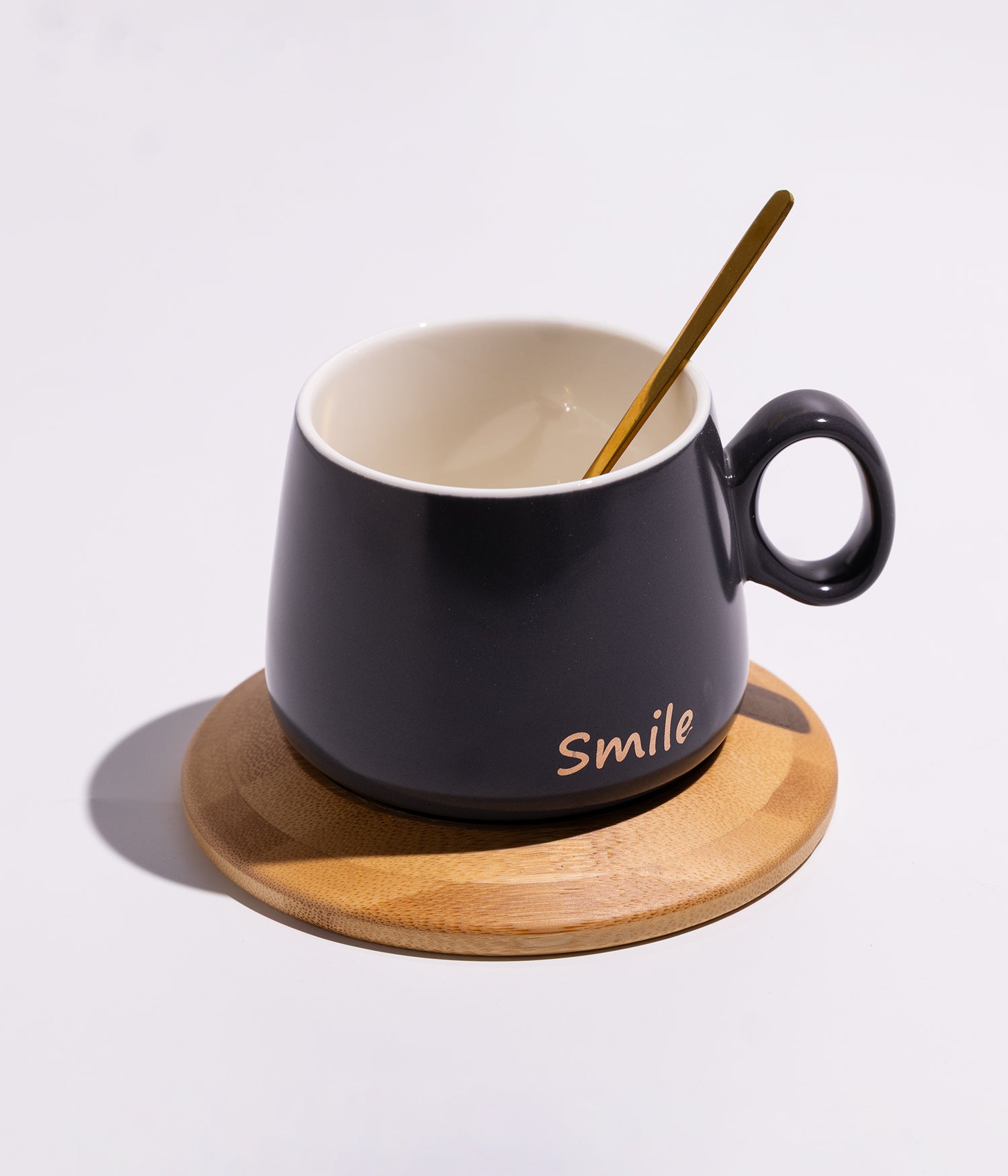 فنجان سيراميك بعبارة «SMILE» مع قاعدة خشبية دائرية وملعقة بلون أسود
