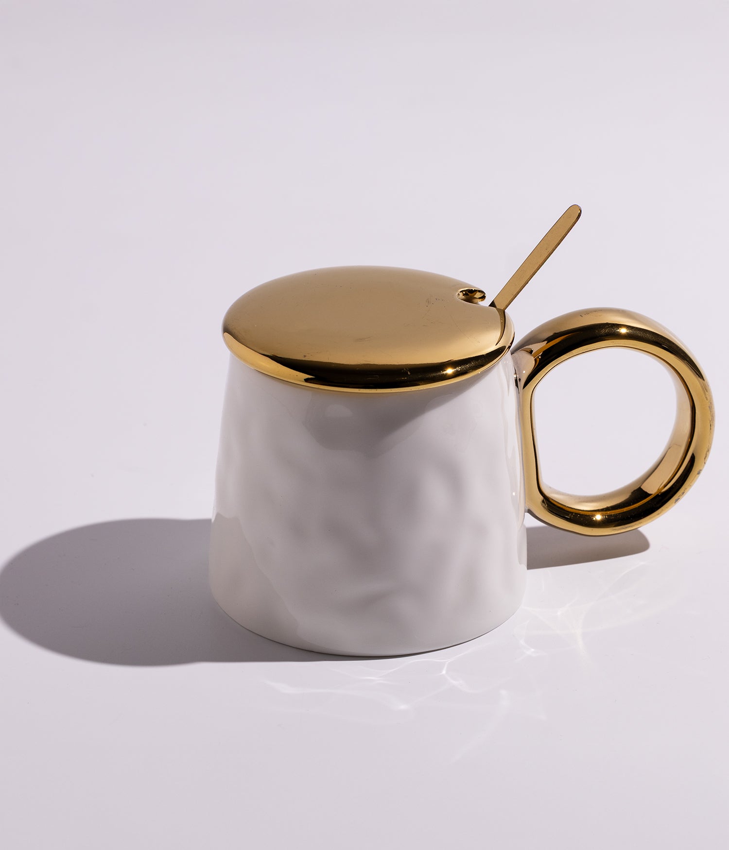 كوب سيراميك بتصميم أنيق مع غطاء ومقبض ميتاليك، مرفق بملعقة معدنية ملونة، باللون الأبيض مع غطاء ذهبي