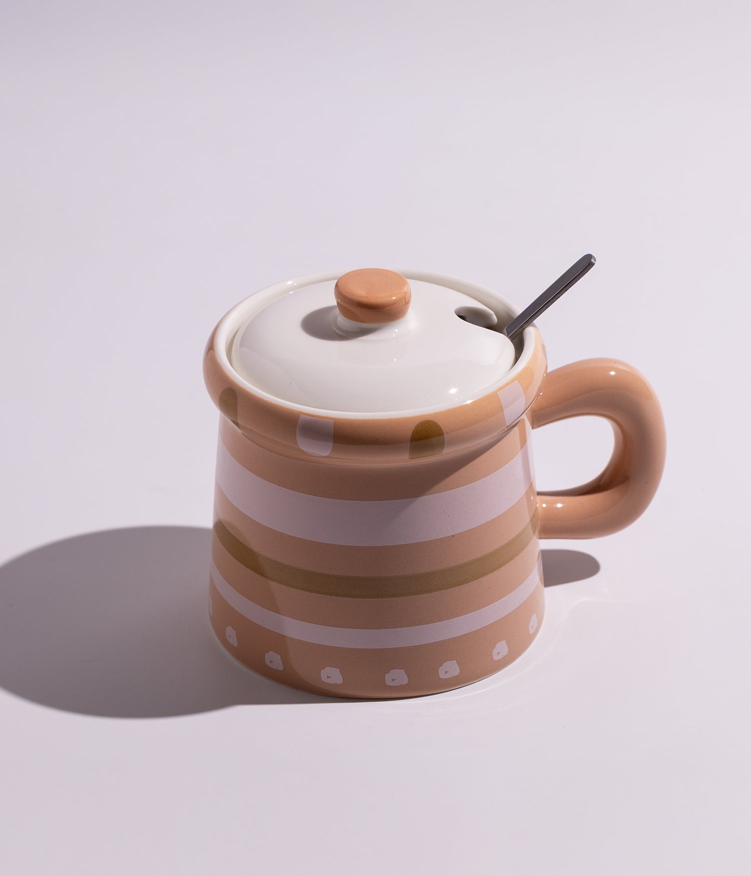 كوب من السيراميك بتصميم مستوحى من قدور الطهي، مزود بغطاء وملعقة، مناسب لتقديم المشروبات الساخنة بطريقة مبتكرة