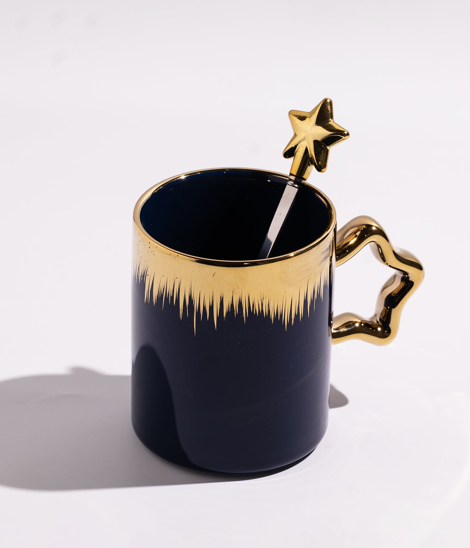 كوب مصنوع من السيراميك باللون الكحلي مزين بخطوط سنابل ذهبية، يأتي مع ملعقة على شكل نجمة، مناسب للاستخدام اليومي مع القهوة أو الشاي