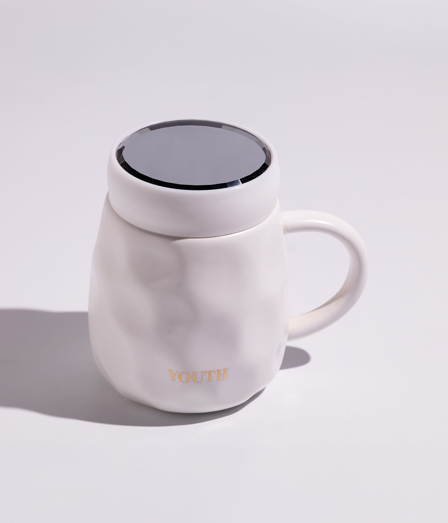 كوب قهوة سيراميك بتصميم عملي مع غطاء حافظ للحرارة، مزين بكلمة YOUTH باللون الذهبي، باللون الأبيض