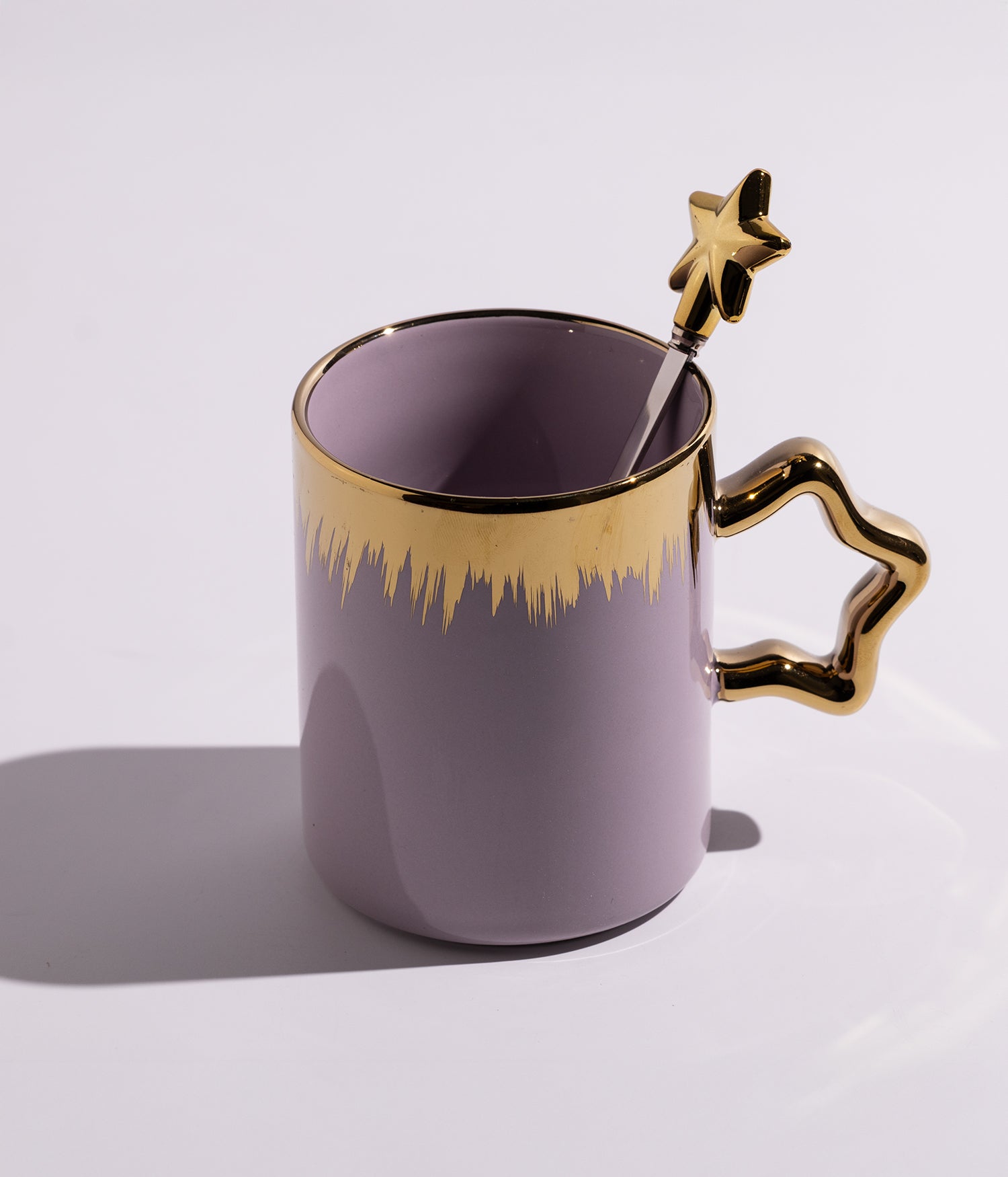 كوب سيراميكي باللون البنفسجي مزين بخطوط سنابل ذهبية، مزود بملعقة بتصميم نجمة، مناسب للاستخدام اليومي مع مختلف المشروبات