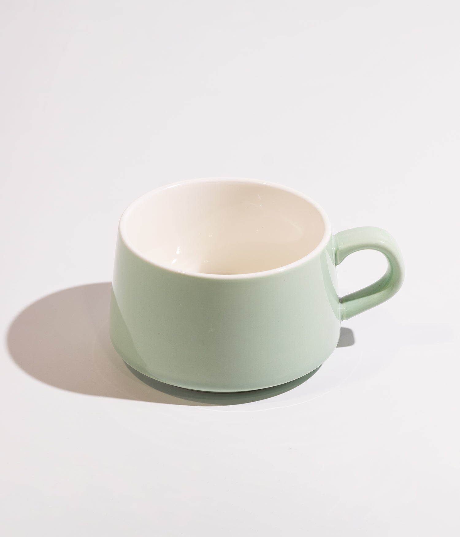 Light green ceramic cup with wooden base and spoon