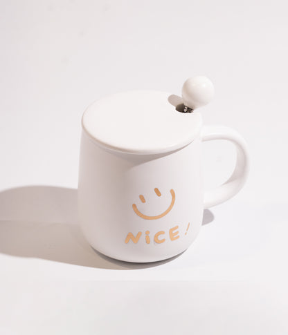 كوب سيراميكي بتصميم وجه مبتسم مع كلمة NICE، متوفر باللون الأبيض ويأتي مع غطاء مخصص لحفظ الحرارة وملعقة، ملائم للاستخدام اليومي في المنزل أو المكتب