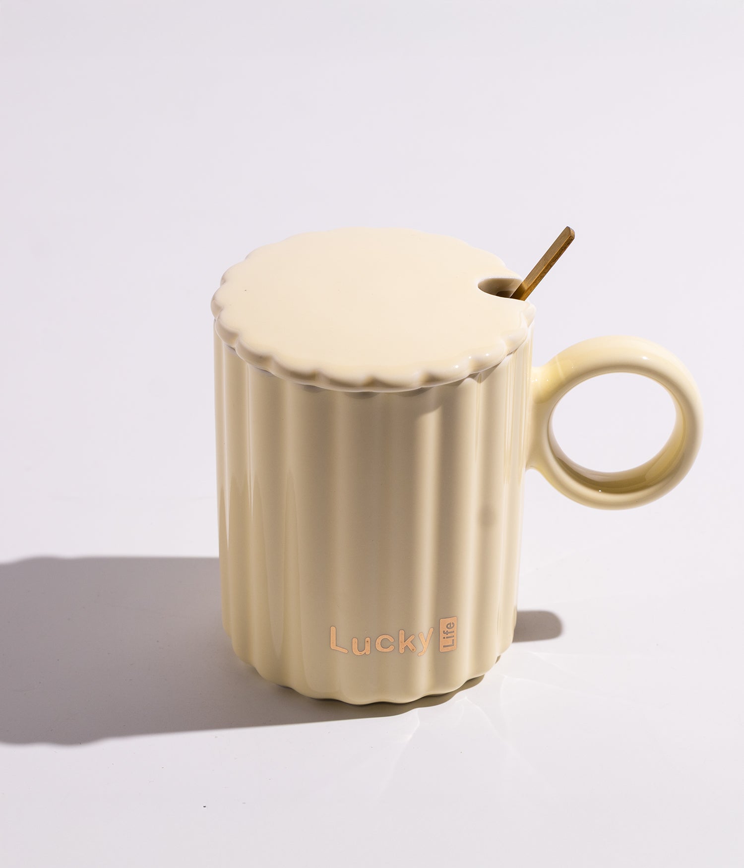 كوب مصنوع من السيراميك باللون الأصفر مزين بخطوط عصرية، مزود بغطاء وملعقة، مناسب للاستخدام اليومي مع القهوة أو الشاي